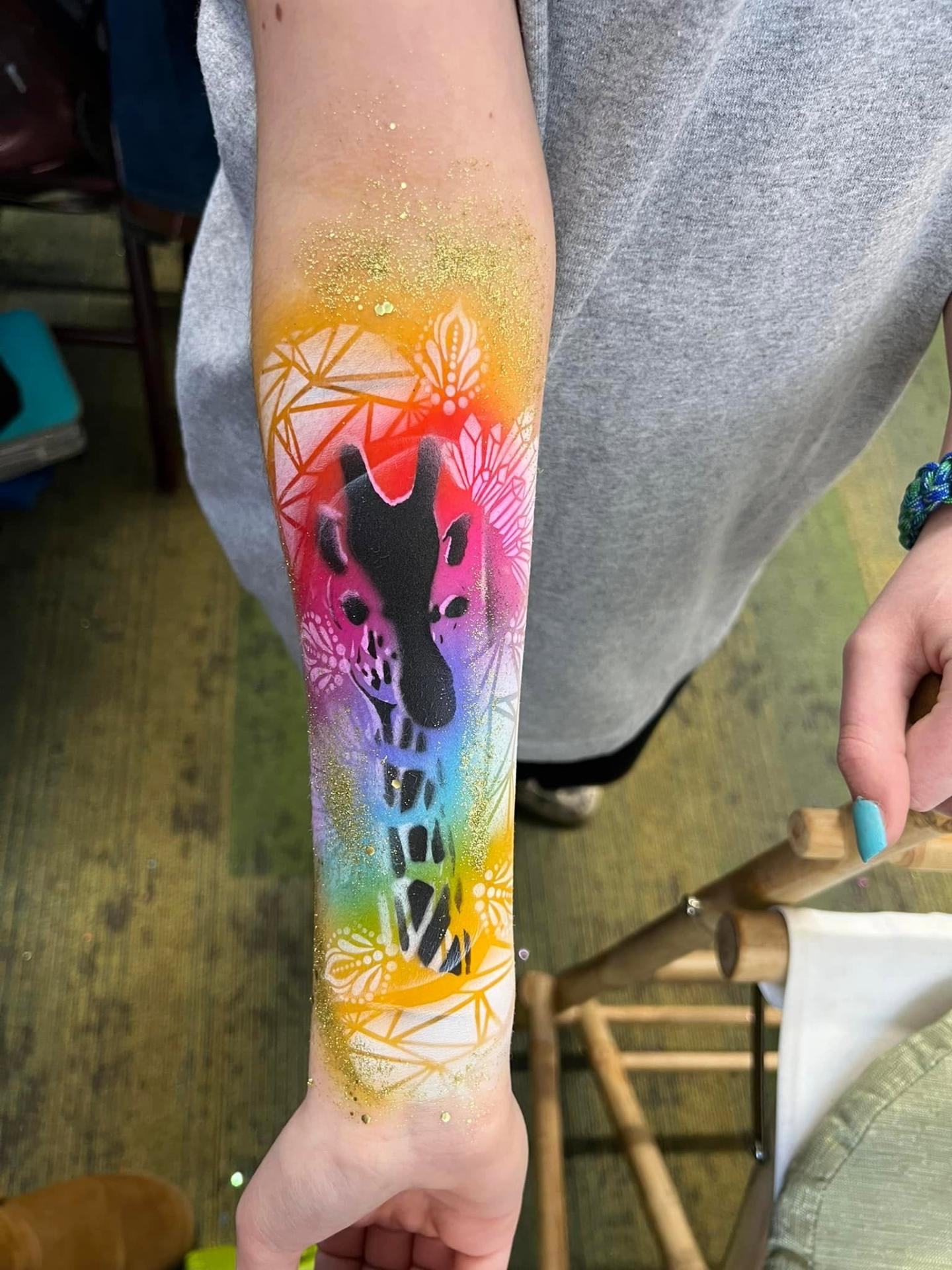 Rainbow airbrush giraffe design painted along a forearm