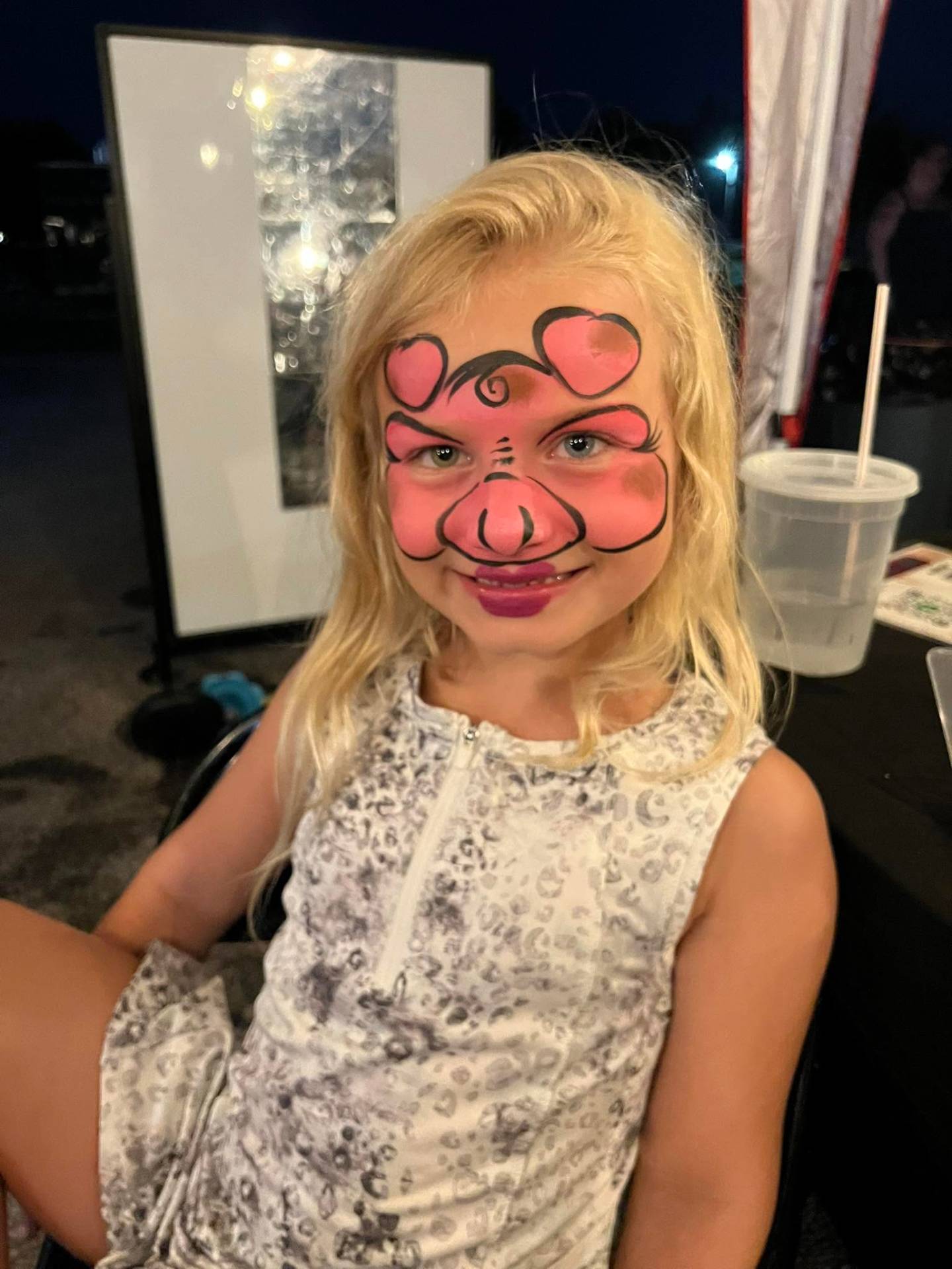 Pink puppy dog face paint on a smiling child