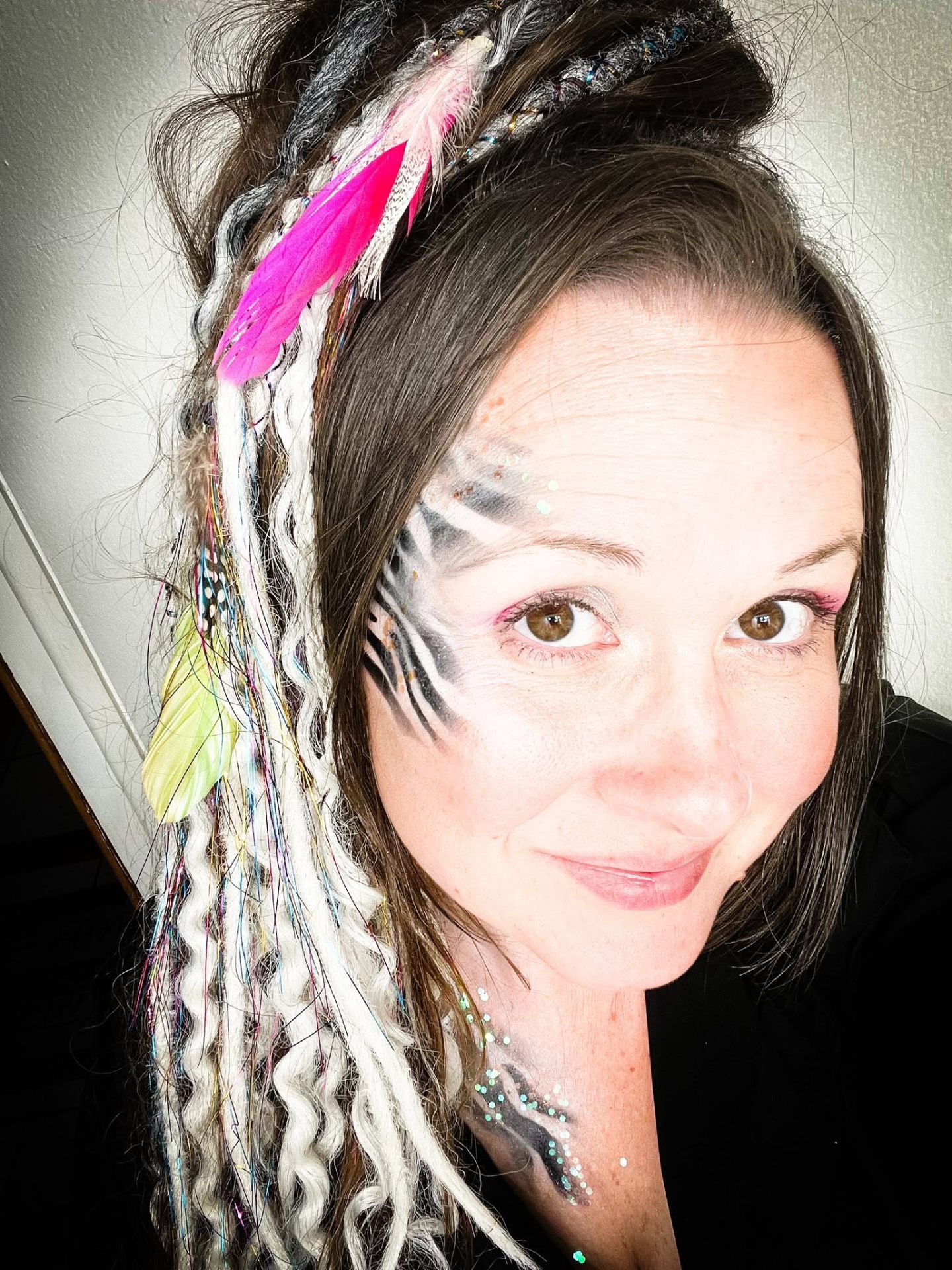 Zebra-inspired face paint with pink accents and glitter