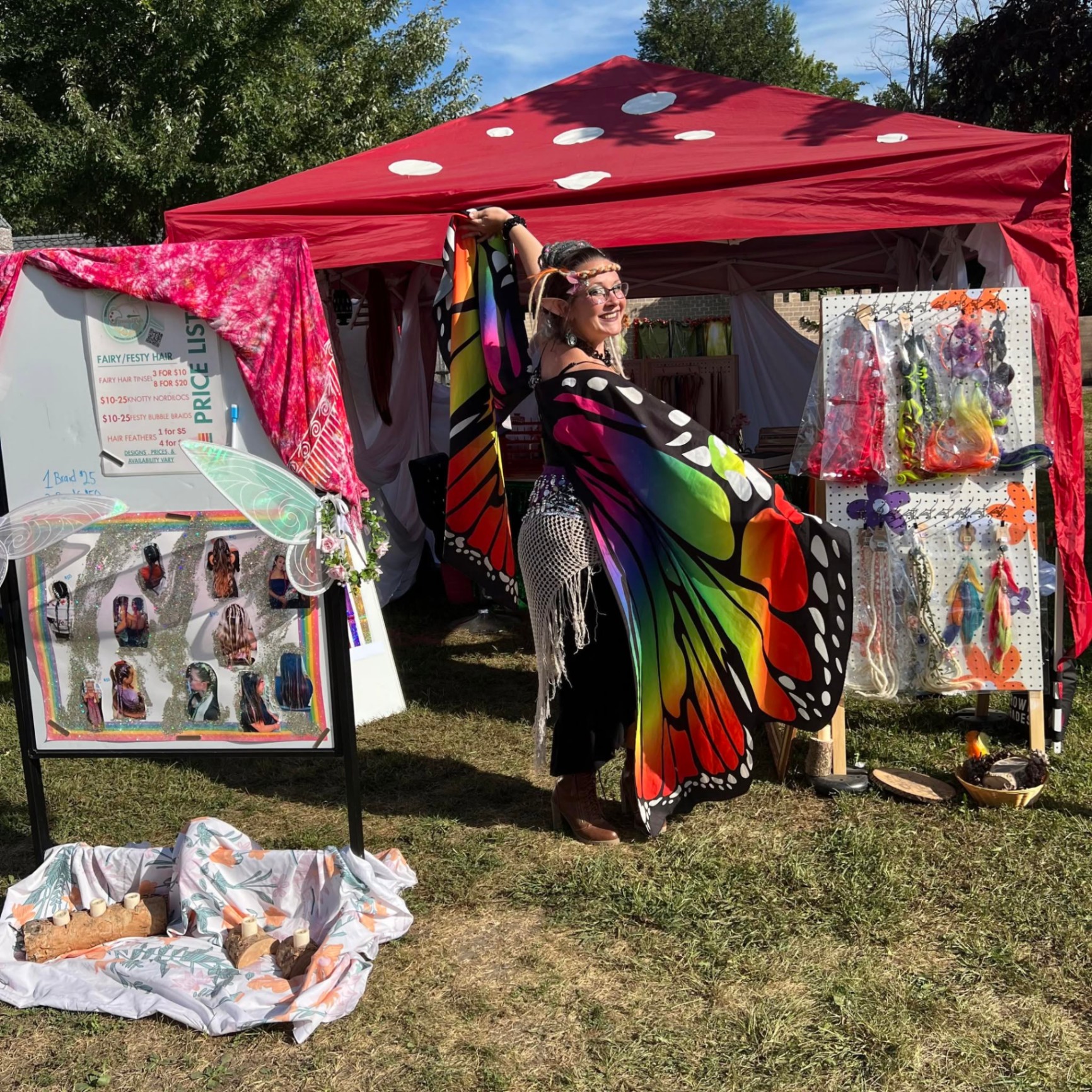 Tiah at her red toadstool tent with butterfly wing cape and fairy hair display
